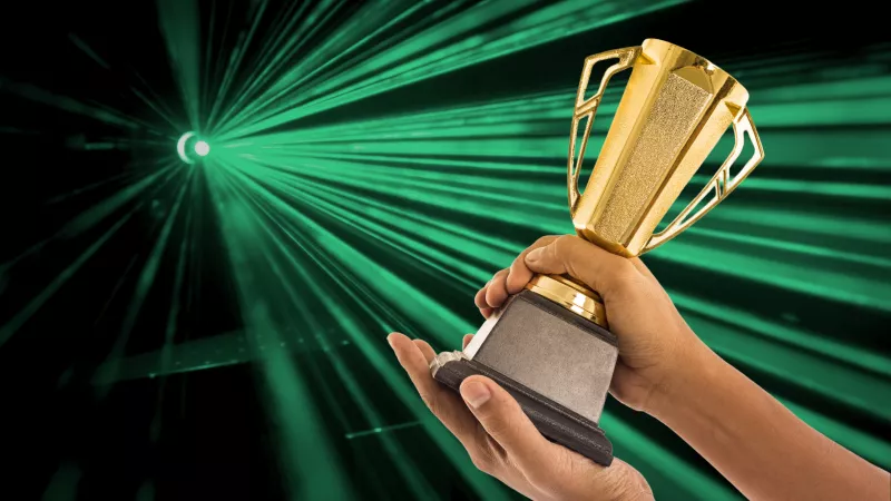 Arany díj az előtérben, a háttérben lézersugarak.