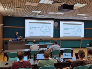 Előadó terem két kivetítővel amiken HUN-REN Cloud logó van. A nézőtéren hallgatóság.
